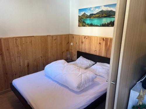 um quarto com uma cama com lençóis brancos e um quadro em La foux d allos Superbe appartement 6 couchages ,piscine em Allos