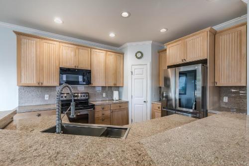 a large kitchen with wooden cabinets and a sink at Beach Access - Golf Cart Included - Views of the Marsh and Harbor River - Sleeps 10 in Harbor Island