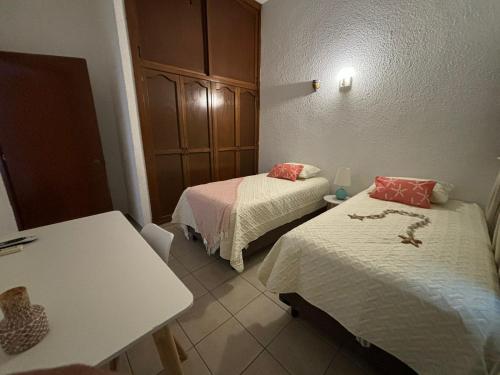 a room with two beds and a table and a table at Departamento en el Área de Olas Altas in Mazatlán