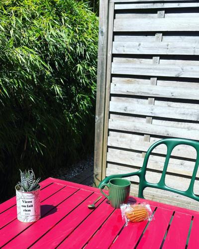 a red picnic table with a green chair and a plant at Le Clos Du Pontic Logis et Cit'Hotel in Landerneau