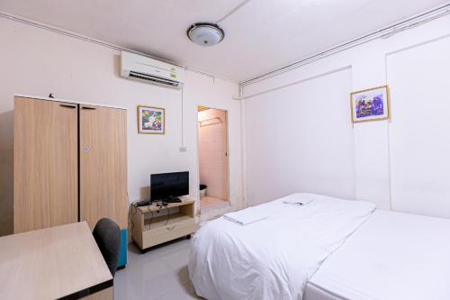 Freesia Saladaeng Silom Apartments في بانكوك: غرفة نوم بسرير ومكتب وتلفزيون