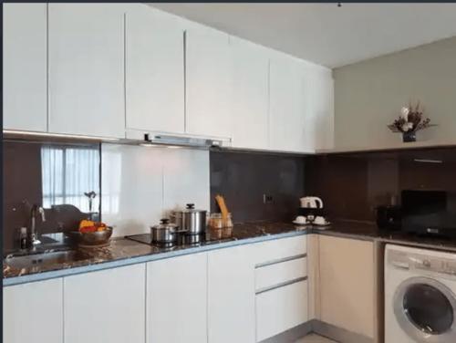 a kitchen with white cabinets and a washing machine at Luxury Apartement Rasuna Jakarta by Lentera in Jakarta