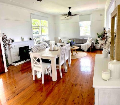 een woonkamer met een witte tafel en stoelen bij Sandon Beach Cottage in Bulli