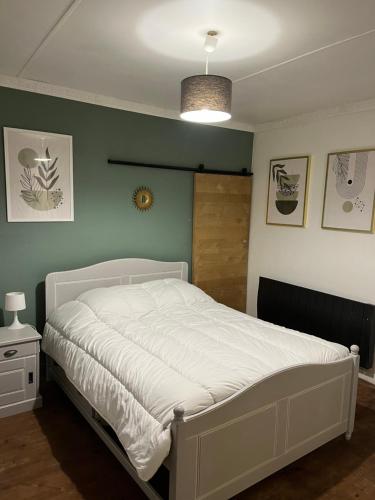 1 dormitorio con cama blanca y pared verde en Petite maison sympa, en Saint-Jean-sur-Mayenne