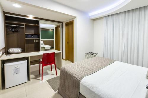 a bedroom with a bed and a desk with a red chair at Centromar Hotel in Balneário Camboriú