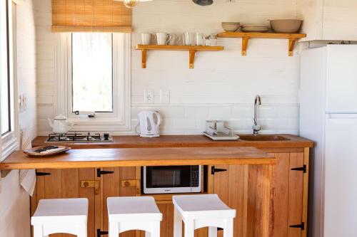 a kitchen with a counter with a microwave and stools at Cabaña Sal de Mar in Punta Del Diablo