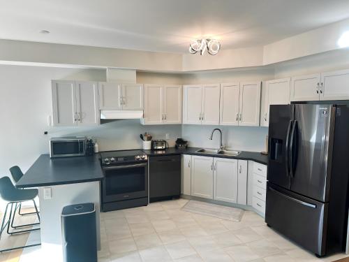 a kitchen with white cabinets and a black refrigerator at 112 Delphi Court - Blue Mountain Escape in Blue Mountains