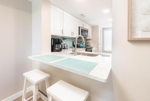 a kitchen with white cabinets and a counter with stools at Newly Listed Immaculate Condo - Distant Ocean Views - Pool and Beach Access in Harbor Island