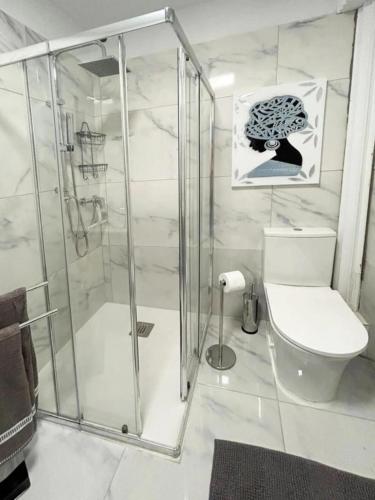 a white bathroom with a shower and a toilet at La Casita de Bonnie in La Tejita