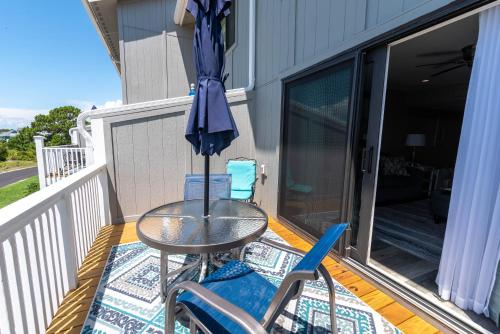 a table and chairs on a balcony with an umbrella at Newly Listed Immaculate Condo - Distant Ocean Views - Pool and Beach Access in Harbor Island