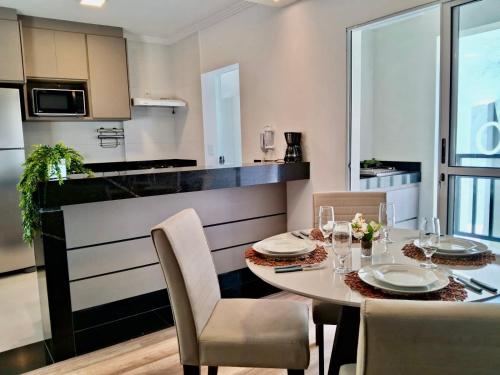 a kitchen with a dining room table and chairs at Suíte confortável, churrasqueira e TV 55in em area nobre da cidade in Poços de Caldas
