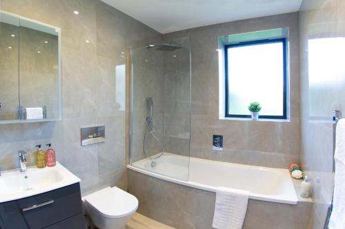 ein Badezimmer mit einer Badewanne, einem WC und einem Waschbecken in der Unterkunft Hendon Luxury Home 1 in Hendon