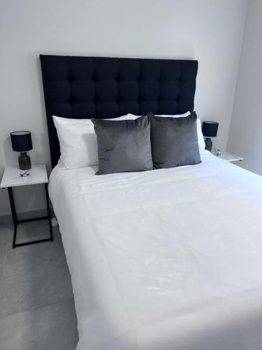a large white bed with a black headboard and pillows at Cosea Langebaan in Langebaan