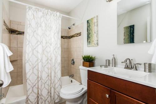 Un baño con inodoro, lavabo y ducha. en Perfect for family visits to Washington DC or UMD!, en College Park