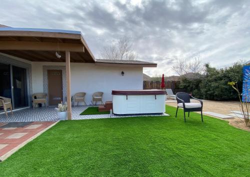 a backyard with a table and chairs on a lawn at Electroliquid's Casa Pueblo Joshua Tree in Joshua Tree