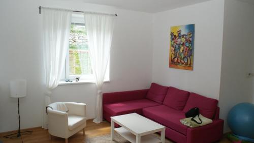 a living room with a red couch and a window at Penzion Emilia in Ružomberok