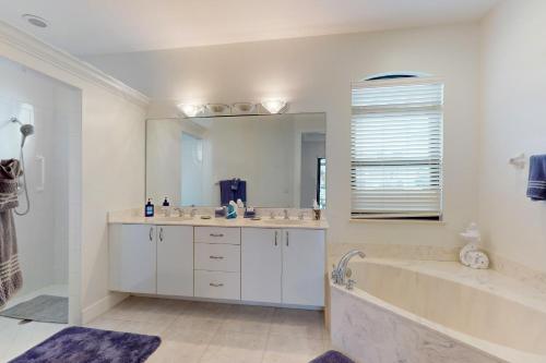 a bathroom with a tub and a large mirror at Driftwood Dreams in Marco Island