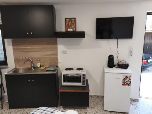 a small kitchen with a sink and a microwave at Ξενώνας museum ισόγειο στο Ελληνικό Ιωαννίνων in Kalentzi