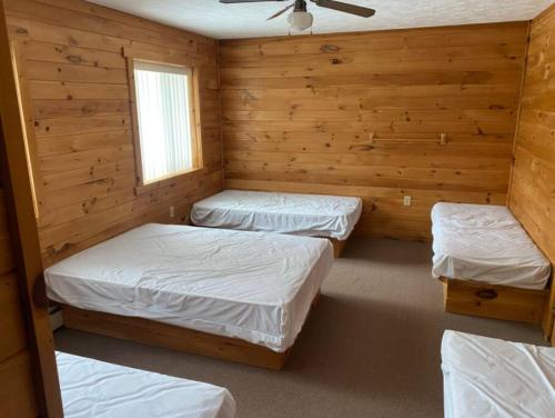 three beds in a room with wooden walls at Brimley Lodge / Sleeps 36 / Snowmobile & ORV Trail in Brimley