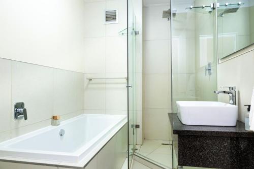 a bathroom with a sink and a glass shower at Sea Spray A308 by Host Agents in Bloubergstrand