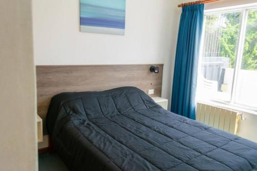 ein Schlafzimmer mit einem Bett mit einer blauen Decke und einem Fenster in der Unterkunft Dpto. Centrico con Vista al Lago in San Carlos de Bariloche