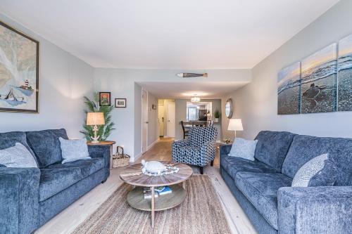 a living room with blue couches and a table at New Listing - Overlooking the Pool with Beach Views in Harbor Island