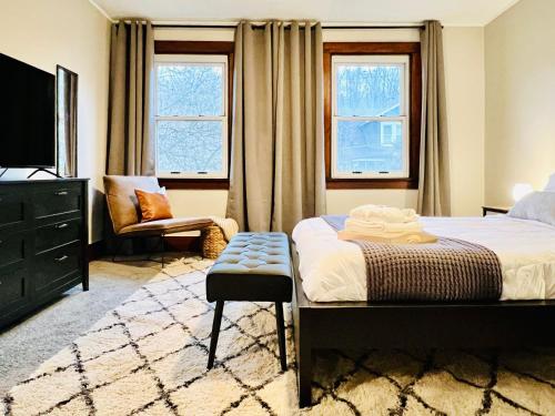 a bedroom with a bed and a chair and two windows at Allegheny Retreat Close to Downtown in Pittsburgh