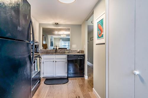 a kitchen with white cabinets and a black refrigerator at New Listing - Overlooking the Pool with Beach Views in Harbor Island