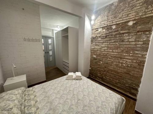 een slaapkamer met een bed en een bakstenen muur bij Rosario Apartament 4Px2b Wifi in Valencia