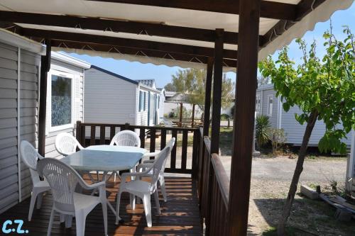 a wooden deck with a table and white chairs at Mobile-home les pieds dans l'eau in Palavas-les-Flots