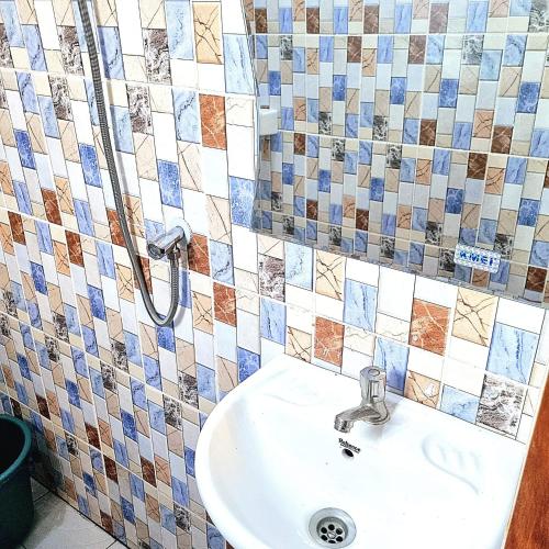 a bathroom with a sink and tiles on the wall at Residence Sighaka - Luxus VIP Apartment - WiFi, Gardien, Parking in Douala