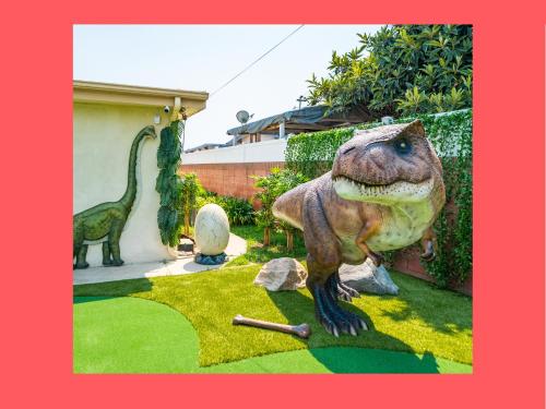 a statue of a dinosaur standing in a yard at Dino Disneyland: Arcade, Playground & More!! in Garden Grove