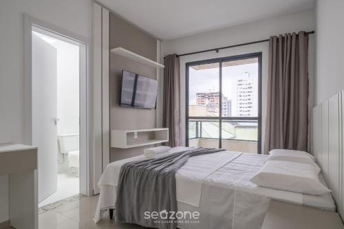 una camera con un letto e una grande finestra di Apto confortável a 3min da Praia RGO0502 a Itapema