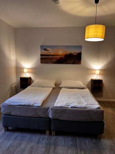 two beds in a bedroom with two lamps and a painting at Landhof Belka in Hoyerswerda