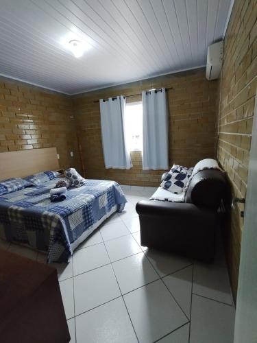 a bedroom with a bed and a chair in it at CASA DE PRAIA ILHA in Araranguá