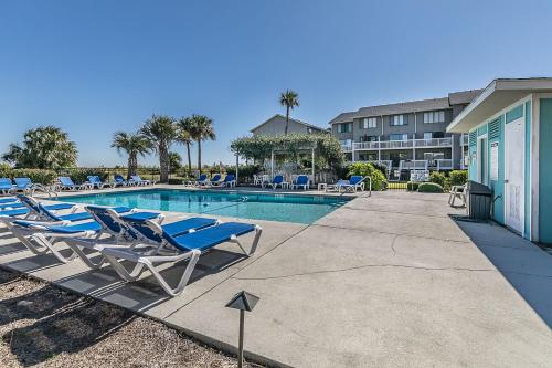 a swimming pool with lounge chairs next to a building at First Floor Condo - Walking distance to beach and pools! in Harbor Island