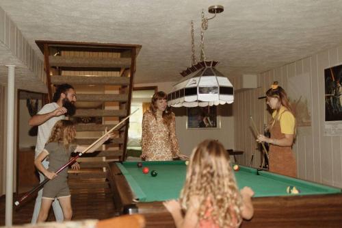 a group of people standing around a pool table at That 70s House at Hidden Creek Estates in Roscoe