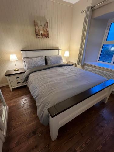 a bedroom with a large bed with two tables and two lamps at Killawalla Cottage, Westport. in Westport