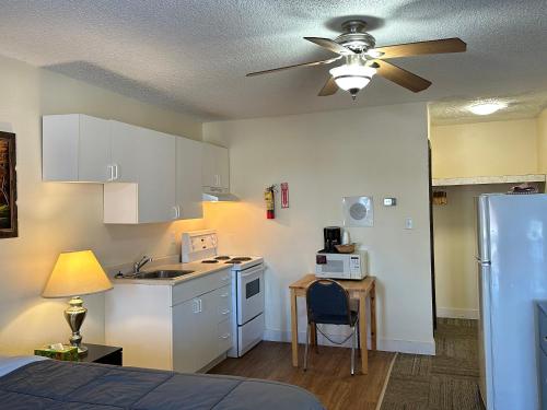 a kitchen with white cabinets and a ceiling fan at Pleasant Valley Motel Houston in Houston
