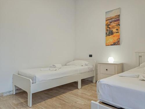 two beds in a room with white walls and wooden floors at Juliet's Terrace on the River in Verona