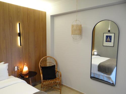 a bedroom with a mirror and a bed and a chair at Hotel Porto Real Aparecida in Aparecida