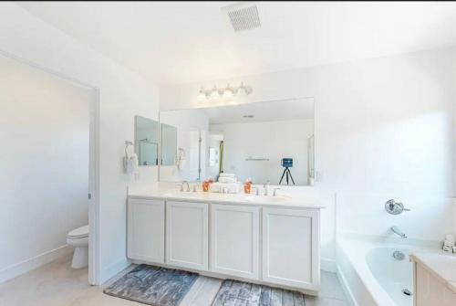 Baño blanco con lavabo, bañera y espejo en The Spotless 2 Story en Phoenix