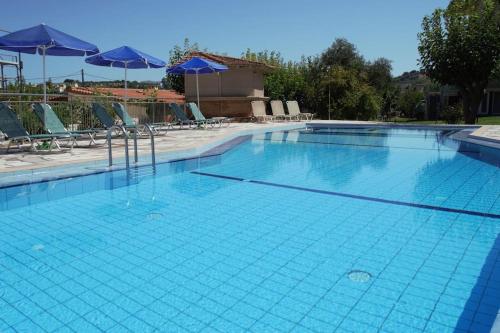 a large blue swimming pool with chairs and umbrellas at Kalliopi Apt in Kavros