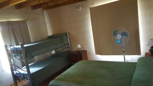 1 dormitorio con 2 camas verdes y ventilador en Calamuchita Lodges en Villa Rumipal