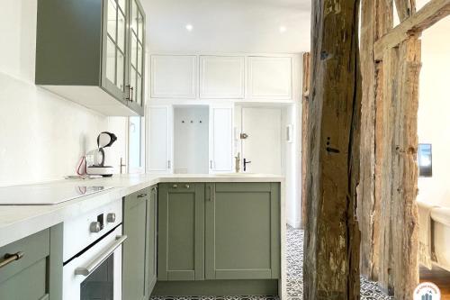 - une cuisine avec des placards verts et blancs et un mur dans l'établissement L'Armateur - Confort - Standing Marché, au Havre