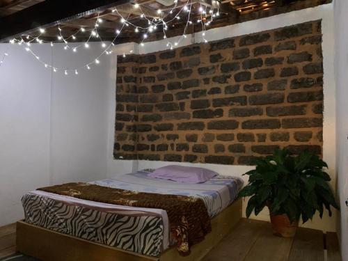 Cama en habitación con pared de ladrillo y luces en Hostel Solar en Mucugê