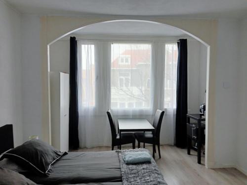 a bedroom with a bed and a table and a window at Studio Slijterij Zandvoort in Zandvoort