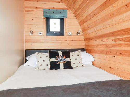 uma cama num quarto com uma parede de madeira em Barry em St Austell