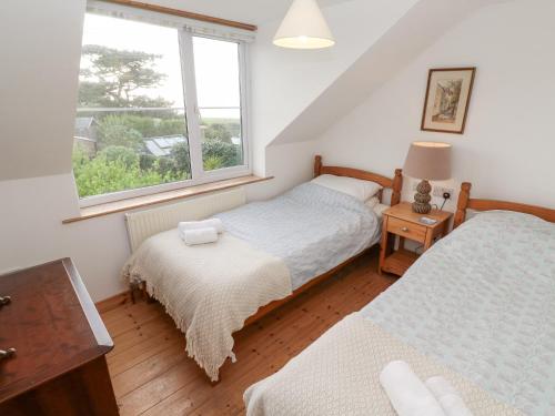 a twin bedroom with two beds and a window at Kernyk in Helston