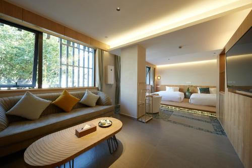 a living room with a couch and a bed at Encounter Hotel - West Lake Hefang Street in Hangzhou